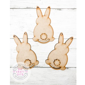 May include: Three unfinished wooden bunny shapes with a small circle cut out for a tail. The bunnies are ready to be painted or decorated.
