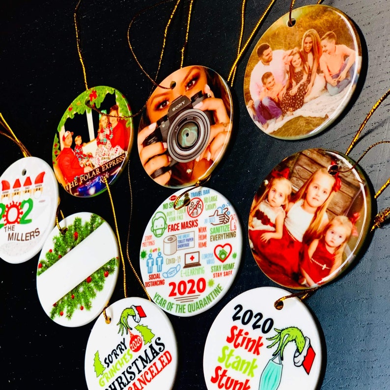 Peut inclure: Un ensemble de dix boules de No&euml;l rondes en c&eacute;ramique blanche avec diff&eacute;rents motifs. Les boules pr&eacute;sentent des images de personnes, du texte et des illustrations. Certains des motifs incluent "The Polar Express", "2020 Ann&eacute;e de la Quarantaine" et "D&eacute;sol&eacute; Grinches No&euml;l 2020 Annul&eacute;".