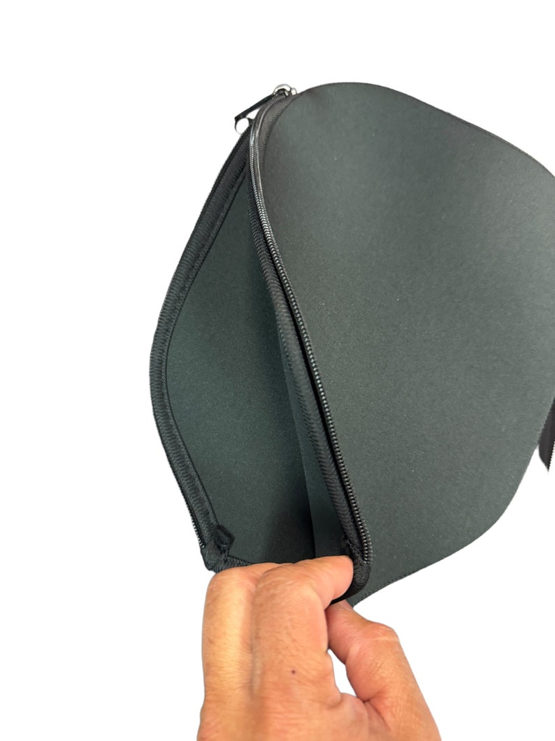 May include: A black zippered laptop sleeve with a soft, padded interior. The sleeve is open and the zipper is visible.