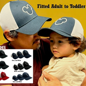 May include: A set of six color options for fitted adult and toddler hats with a Mickey Mouse silhouette embroidered on the front. The hats are made of a mesh fabric with a white brim and a navy blue crown. The text "Fitted Adult to Toddler Hats" and "6 Colors" is visible in the image.