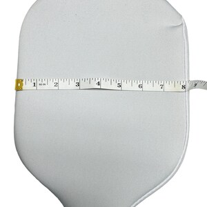 May include: White paddle cover with a zipper closure. The cover is 17.8 cm wide.