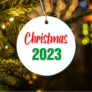 Peut inclure: Boule de No&euml;l ronde blanche avec le texte rouge "Christmas" et le texte vert "2023".