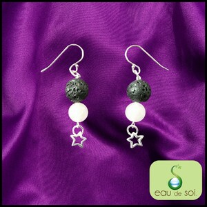 Peut inclure: Une paire de boucles d'oreilles en argent avec des perles de lave noire et des perles blanches, chacune se terminant par un charme d'étoile en argent.