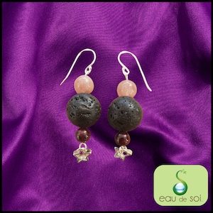 Peut inclure: Une paire de boucles d'oreilles en argent avec trois perles chacune. La perle du haut est de couleur rose clair, la perle du milieu est de couleur gris foncé et la perle du bas est de couleur marron foncé. Les boucles d'oreilles ont un charme étoile en bas.