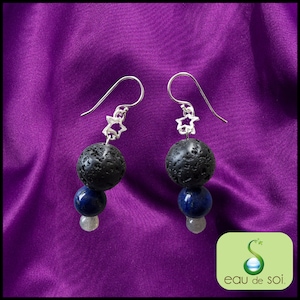 Peut inclure: Une paire de boucles d'oreilles en argent avec un charme en forme d'étoile et trois perles. La perle du haut est en lave noire, la perle du milieu est en lapis-lazuli bleu foncé et la perle du bas est en pierre de lune gris clair.