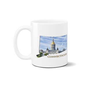 May include: White ceramic coffee mug featuring a graphic of the Connecticut state outline with the state capitol building in Hartford. The text "CONNECTICUT" is printed in gold below the image.