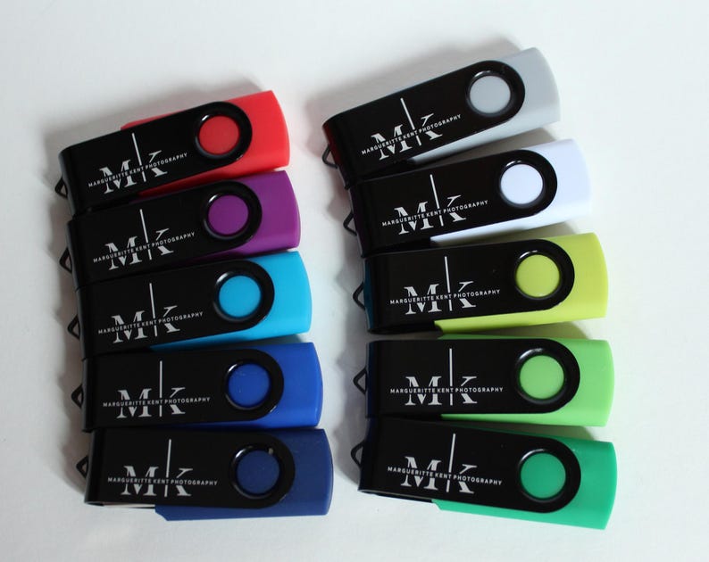 Puede incluir: Una colecci&oacute;n de memorias USB de colores. Cada unidad tiene un cuerpo negro con un bot&oacute;n circular de color y un acento de color a juego. Las unidades est&aacute;n etiquetadas con el texto "MK MARGUERITTE KENT PHOTOGRAPHY" en blanco.