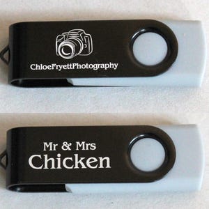 Puede incluir: Dos memorias USB negras y grises. Una tiene un gr&aacute;fico de c&aacute;mara y el texto "ChloeFryettPhotography". La otra tiene el texto "Mr & Mrs Chicken".