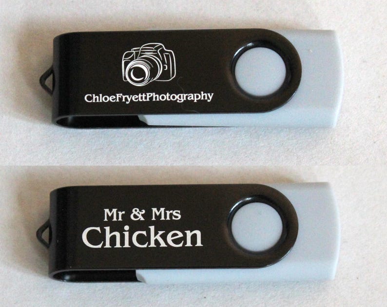 Puede incluir: Dos memorias USB negras y grises. Una tiene un gr&aacute;fico de c&aacute;mara y el texto "ChloeFryettPhotography". La otra tiene el texto "Mr & Mrs Chicken".