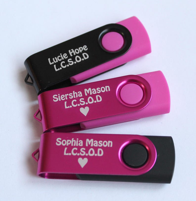 Puede incluir: Tres unidades flash USB en negro y rosa. Cada unidad tiene un dise&ntilde;o giratorio y presenta un nombre e iniciales en texto blanco. Dos unidades son rosas con un bot&oacute;n rosa y una es negra con un bot&oacute;n rosa.