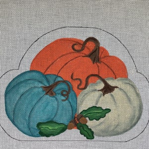May include: Three pumpkins in a circle, one is orange, one is blue, and one is white. They have brown stems and green leaves.