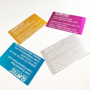 May include: Four business cards with a silver, gold, pink, and blue metallic finish. The cards have white text that reads "SUNTEC LASER TECHNOLOGY" and includes contact information for the company. The text on the cards reads "Laser Engraved Plate" and "Laser Engraved Name Card".