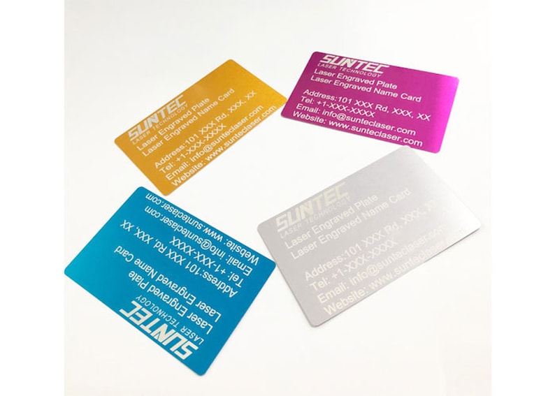 May include: Four business cards with a silver, gold, pink, and blue metallic finish. The cards have white text that reads "SUNTEC LASER TECHNOLOGY" and includes contact information for the company. The text on the cards reads "Laser Engraved Plate" and "Laser Engraved Name Card".