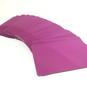 May include: A stack of blank, magenta-colored plastic cards fanned out in a semi-circle.