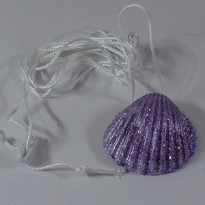May include: A purple seashell necklace with a white cord. The seashell has a glittery finish.
