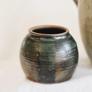 May include: A set of three ceramic mugs with a speckled, matte finish. The mugs are in shades of cream, light gray, and dark gray. Each mug has a simple, minimalist design, perfect for coffee or tea.