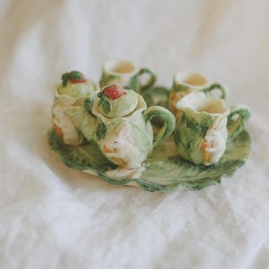 May include: A set of three ceramic mugs with a speckled, matte finish. The mugs are in shades of cream, light gray, and dark gray. Each mug has a simple, minimalist design, perfect for coffee or tea.