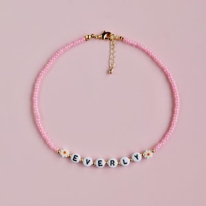 Collar con nombre, de color rosa y cuentas de margaritas.