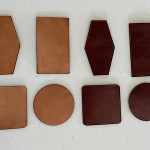 May include: Eight leather pieces in various shapes and sizes. Four are brown and four are burgundy. The shapes include a rectangle, square, circle, and a rounded rectangle.