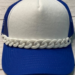 May include: A white and royal blue trucker hat with a white plastic chain detail around the brim.