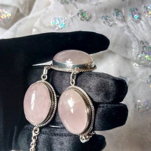 Pu&ograve; includere: Un set di gioielli in quarzo rosa con un anello, un braccialetto e un paio di orecchini. I gioielli sono in argento sterling e presentano pietre di quarzo rosa di forma ovale.
