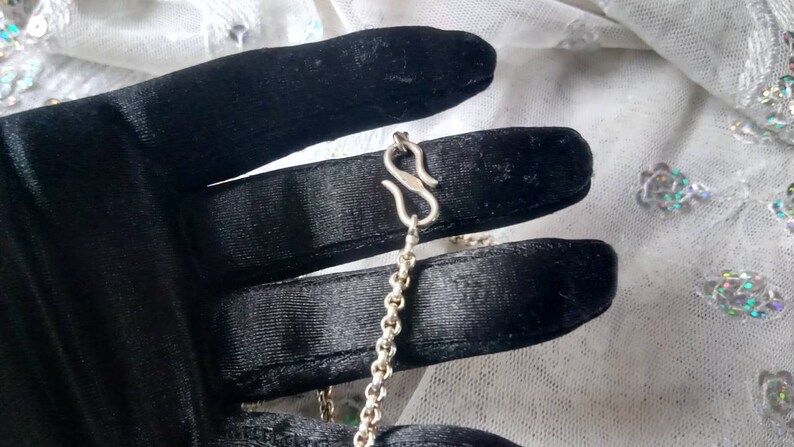 Pu&ograve; includere: Una collana a catena d'argento con chiusura a moschettone. La catena &egrave; delicata, in stile curb.