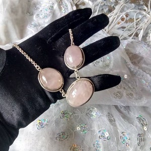 Pu&ograve; includere: Una collana a catena d'argento con tre pietre ovali di quarzo rosa.