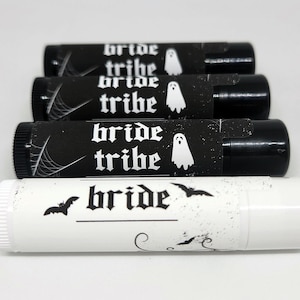 May include: Four black and white lip balm tubes with the text "bride tribe" and a ghost graphic. One white lip balm tube with the text "bride" and a bat graphic.