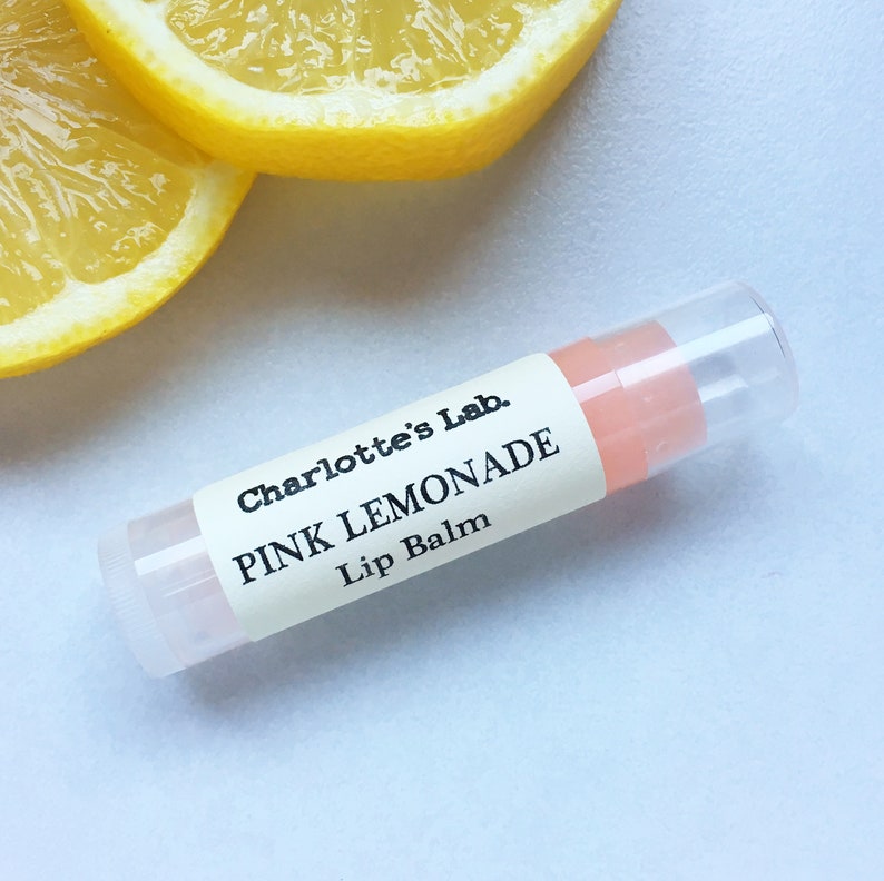 May include: A clear tube lip balm with a white label that reads "Charlotte's Lab. PINK LEMONADE Lip Balm".