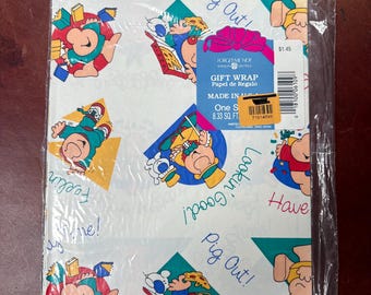 Puede incluir: Papel de regalo en un embalaje de plástico transparente. El papel blanco tiene un patrón repetido de personajes de dibujos animados, con frases como "Feelin' Fine!" y "Pig Out!". El paquete incluye una etiqueta que dice "GIFT WRAP" y "8.33 pies cuadrados".