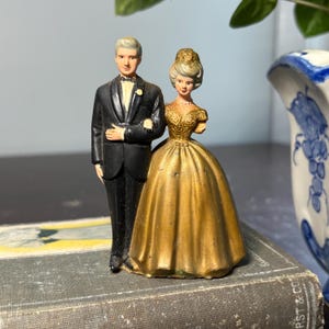 Adorno para tarta de boda del 50 aniversario de Wilton: novios con cabello gris y vestido dorado. Figura de plástico decorativa para centro de mesa. Le falta un brazo.