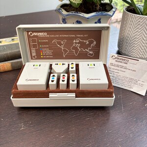 Puede incluir: Un kit de viaje internacional Deluxe Travelcare Norelco vintage. El kit incluye una funda blanca y marrón con un mapa del mundo y varios adaptadores y convertidores de corriente. Diseñado para viajes internacionales, incluye convertidores de 50W y 1600W.