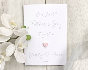 May include: A white card with the text "Our First Father's Day Together. Daddy & Aria 2019" in gray script. A small pink heart is glued to the card.