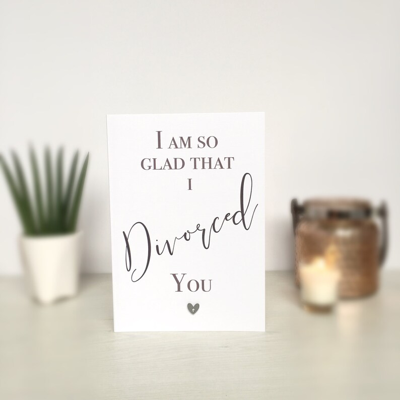 May include: A white card with the text "I am so glad that I divorced you" in black cursive font. A small silver heart is below the text.