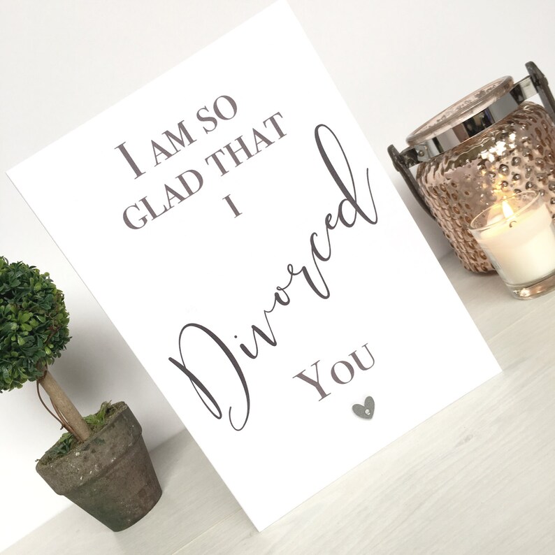 May include: White card with the text "I am so glad that I divorced you" in grey lettering. A small silver heart is below the text.