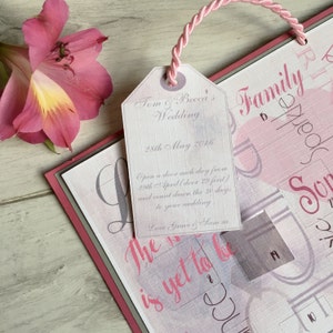 May include: A pink and white wedding countdown calendar with a tag that reads "Tom & Becca's Wedding, 28th May 2016". The tag has the text "Open a door each day from 29th April (door 29 first) and count down the 30 days to your wedding. Love Grace & Sam."