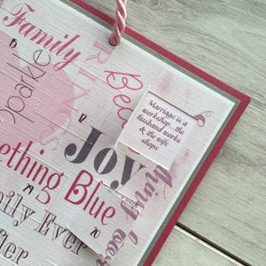 May include: A pink and white sign with the words "Family" and "Joy" in large, bold letters. The sign also includes the text "Marriage is a workshop... the husband works & the wife shops" and "Something Blue" in smaller, decorative fonts.