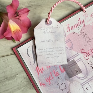 May include: A pink and white wedding countdown calendar with a tag attached. The tag says "Tom & Becca's Wedding" and "28th May 2016". The calendar has a pink and white design with the words "Family Sparkle" and "The Love is yet to be".