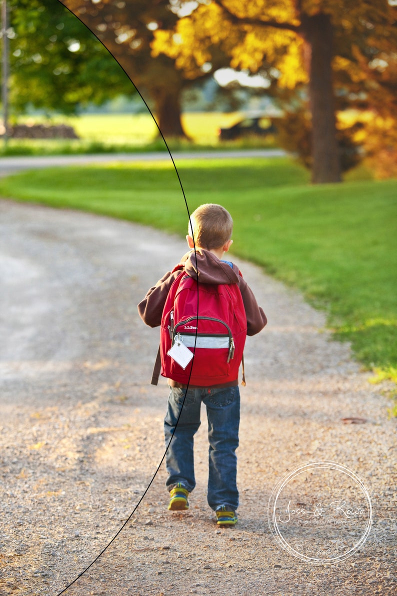 May include: A young person wearing a red backpack with a white tag walks down a gravel path. The path is lined with green grass and trees.