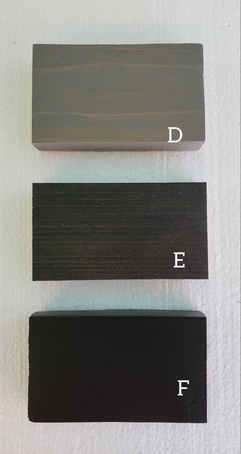 May include: Three wood samples, labeled D, E, and F. The top sample is a light gray wood, the middle sample is a dark gray wood, and the bottom sample is a black wood.