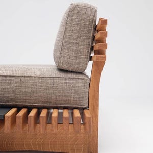 May include: A wooden chair with a slatted back and seat, upholstered in a light brown fabric. The chair has a high back and a curved seat.