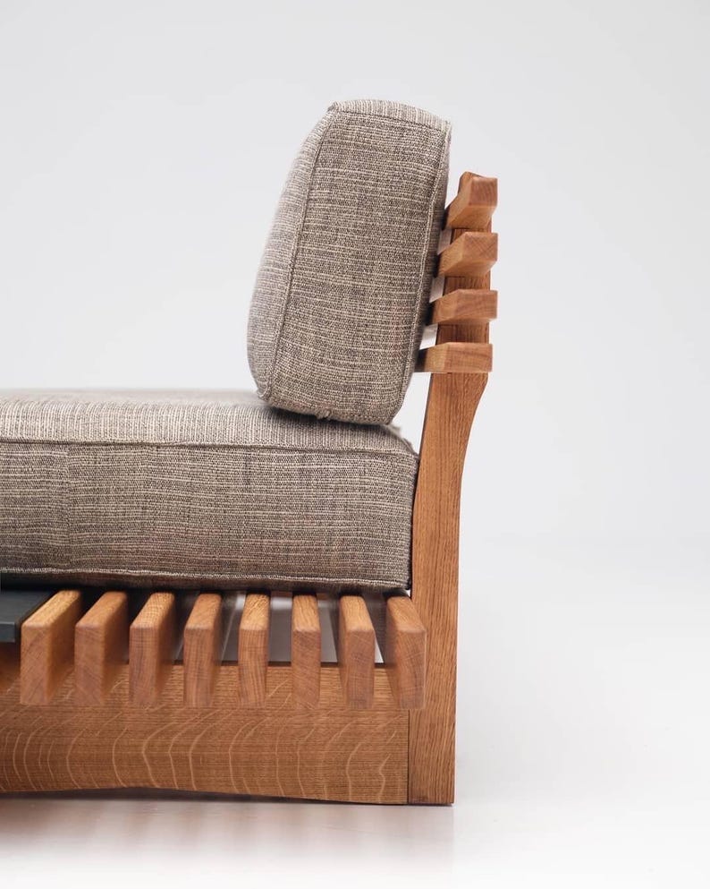 May include: A wooden chair with a slatted back and seat, upholstered in a light brown fabric. The chair has a high back and a curved seat.