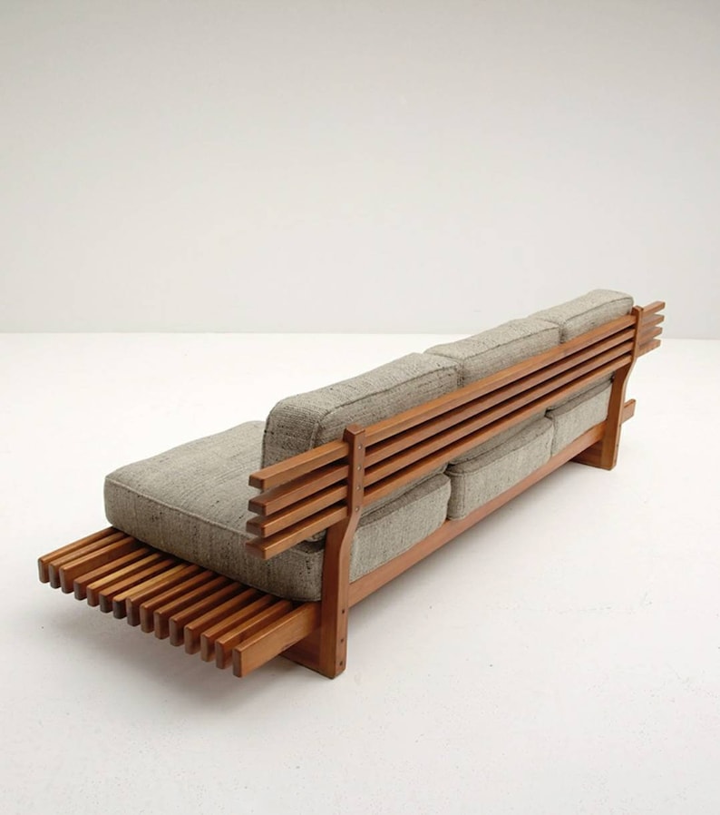 May include: A wooden sofa with a slatted back and a slatted base. The sofa is upholstered in a light gray fabric.