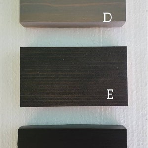 May include: Three wood samples, labeled D, E, and F. The top sample is a light gray wood, the middle sample is a dark gray wood, and the bottom sample is a black wood.