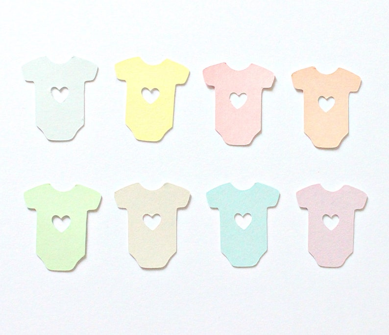 May include: Eight pastel-colored paper cutouts of baby onesies with a heart-shaped hole in the center. The onesies are in shades of blue, green, yellow, pink, and peach.