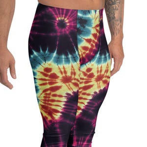 May include: Tie-dye leggings in a spiral pattern with shades of blue, yellow, red, and purple. The leggings are form-fitting and reach the ankles. The person is wearing white sneakers.