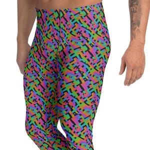 May include: Leggings with a vibrant, geometric pattern in shades of purple, green, blue, and black. The leggings are form-fitting and made of a stretchy material. The model is wearing white sneakers.