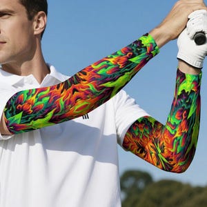 May include: A person wearing a white polo shirt and colorful arm sleeves. The sleeves feature a vibrant design with green, orange, yellow, and red hues. The sleeves are branded with the text "7BYTE CLOTHING".