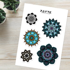 May include: Five colorful mandala stickers on a white sheet of paper. The stickers feature intricate designs in shades of blue, green, purple, and black. The paper has the text "73YTE CLOTHING" printed in black at the top.