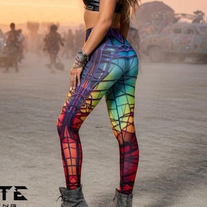Pode incluir: Uma mulher usando um top preto e leggings coloridas com um design geométrico. As leggings apresentam um gradiente de arco-íris de cores. A imagem também mostra um par de botas cinzentas e o logotipo "PSYTE CLOTHING".